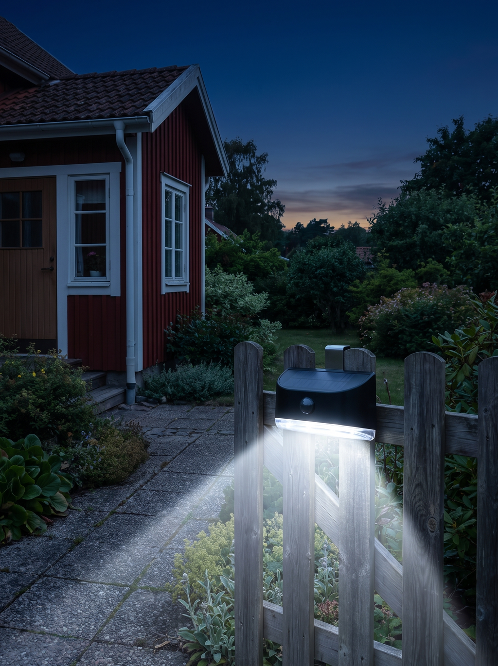 Solcellslampa med rörelsesensor som lyser upp gången vid ett hus på kvällen