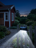 Solcellslampa med rörelsesensor som lyser upp gången vid ett hus på kvällen